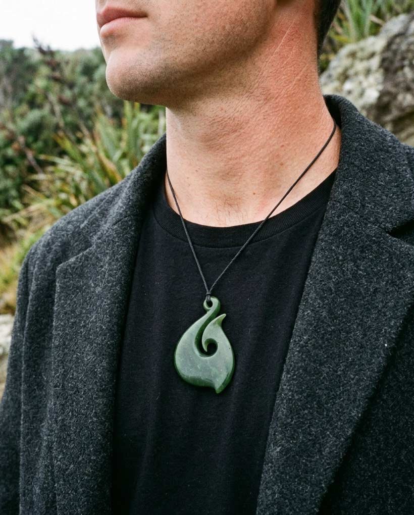 Close-up of a man wearing a pounamu hei matau fish hook necklace
