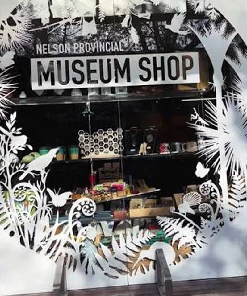 Nelson Provincial Museum Shop window decorated with cut-out native birds, ferns and koru designs