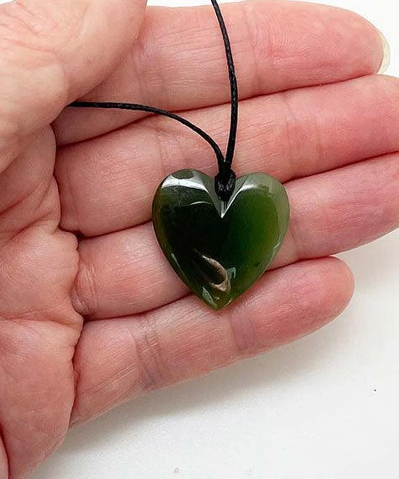 Pounamu heart pendant held in an open hand to show its size, from ShopNZ