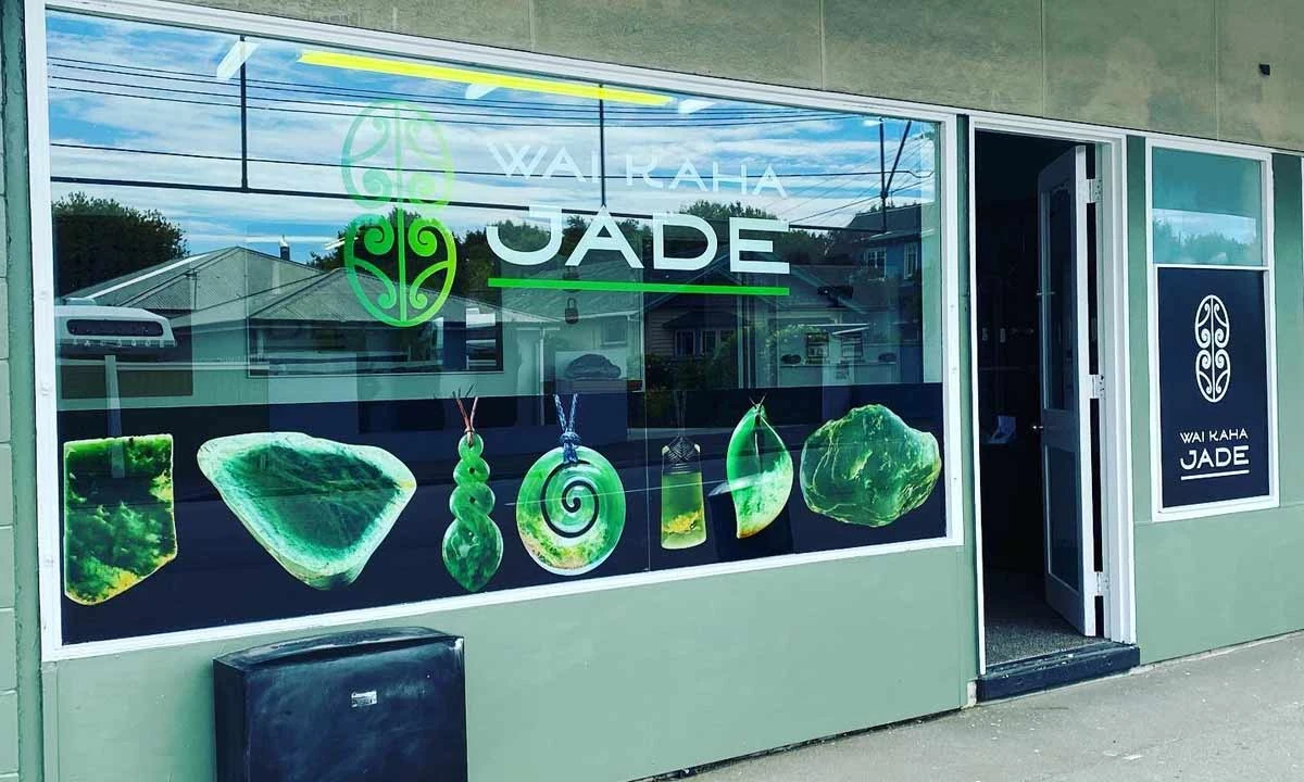 Shopfront window branded Wai Kaha Jade, the studio's earlier name, with large images of pounamu pendants
