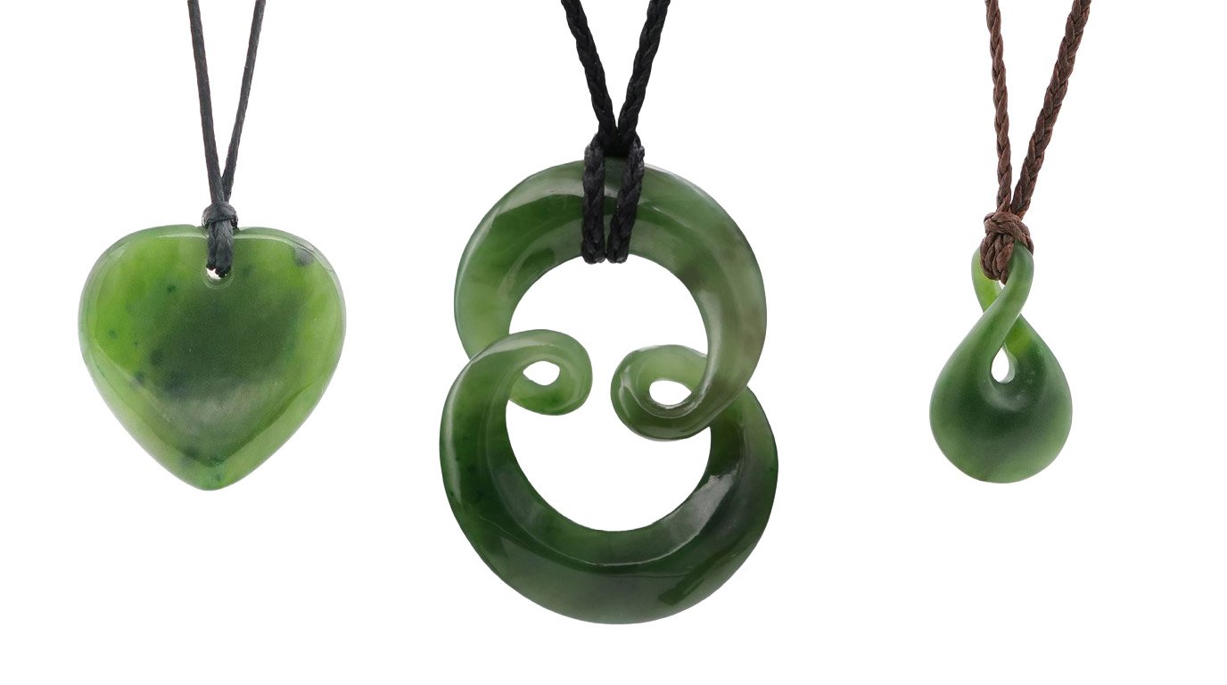 Three kahurangi pounamu pendants on cords: a heart, a double koru and a twist, showing translucent green stone
