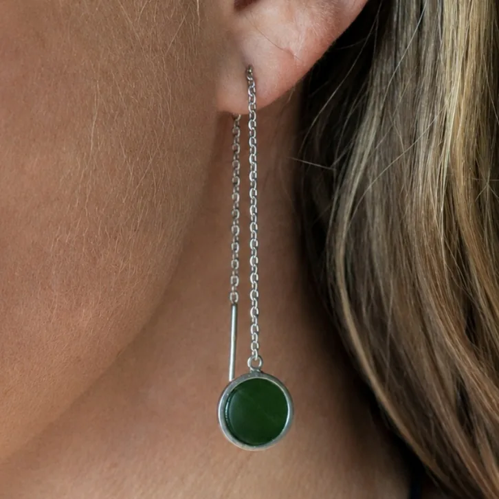 Round pounamu thread earring set in silver on a fine chain, worn on the ear